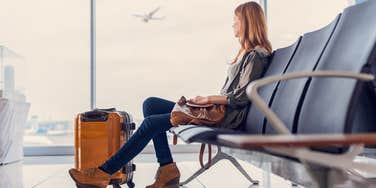 solo woman in airport watching plane take off